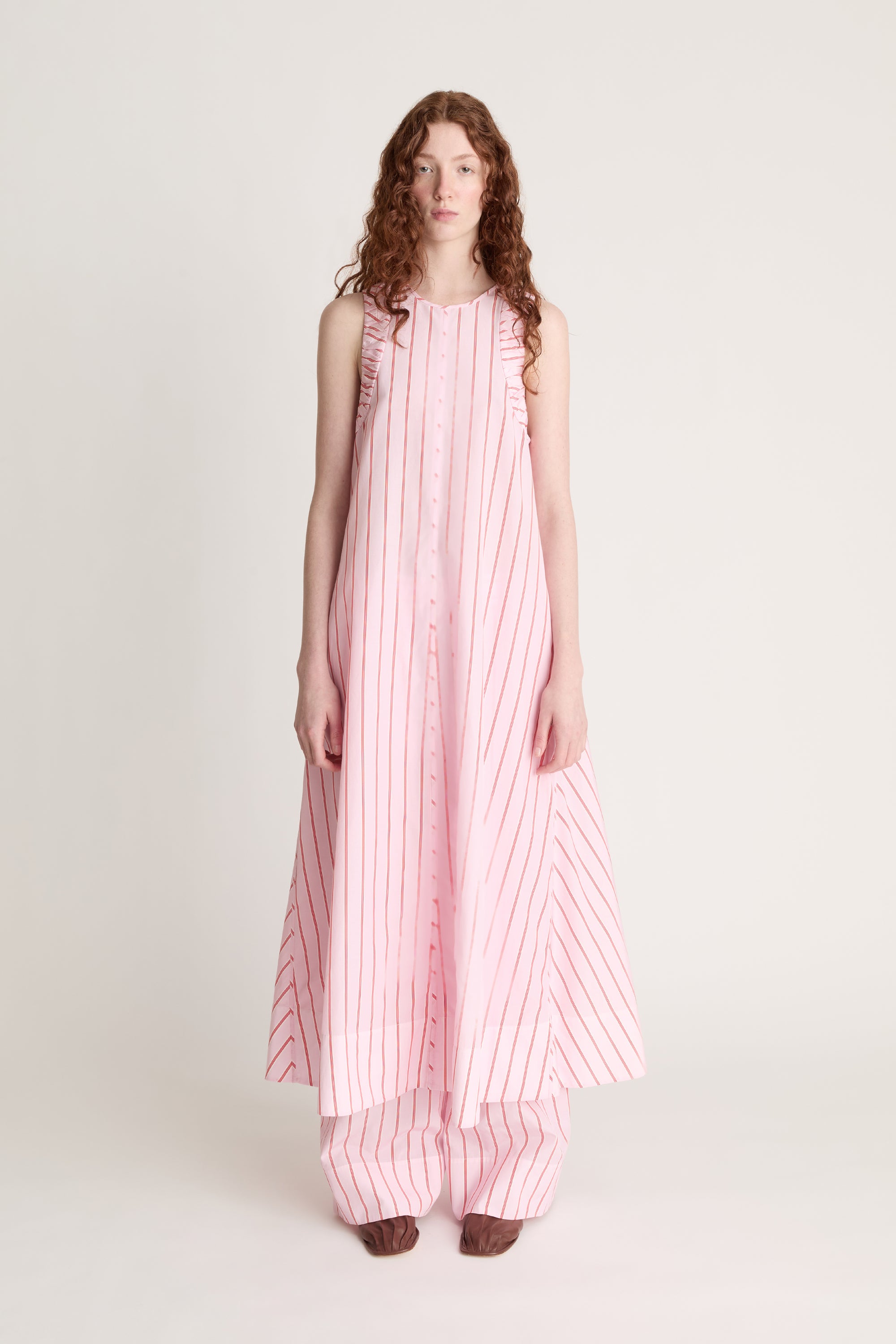 Woman wearing a pink and white striped dress on a white background