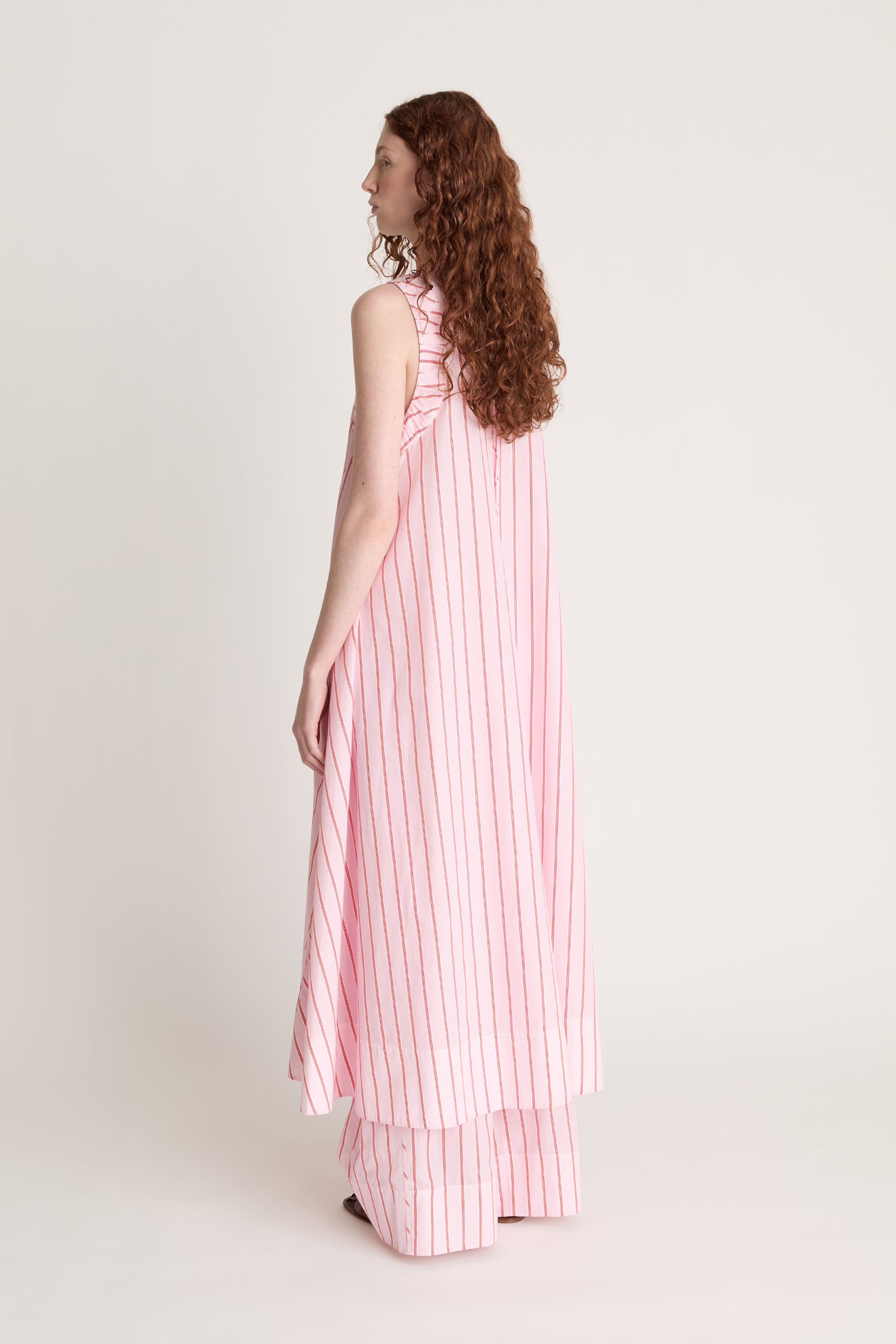 Woman wearing a pink and white striped dress on a white background