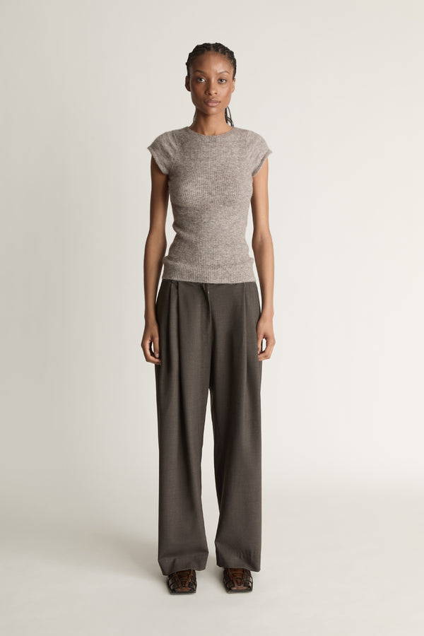 Woman wearing a gray knit top and wide-leg pants on a white background