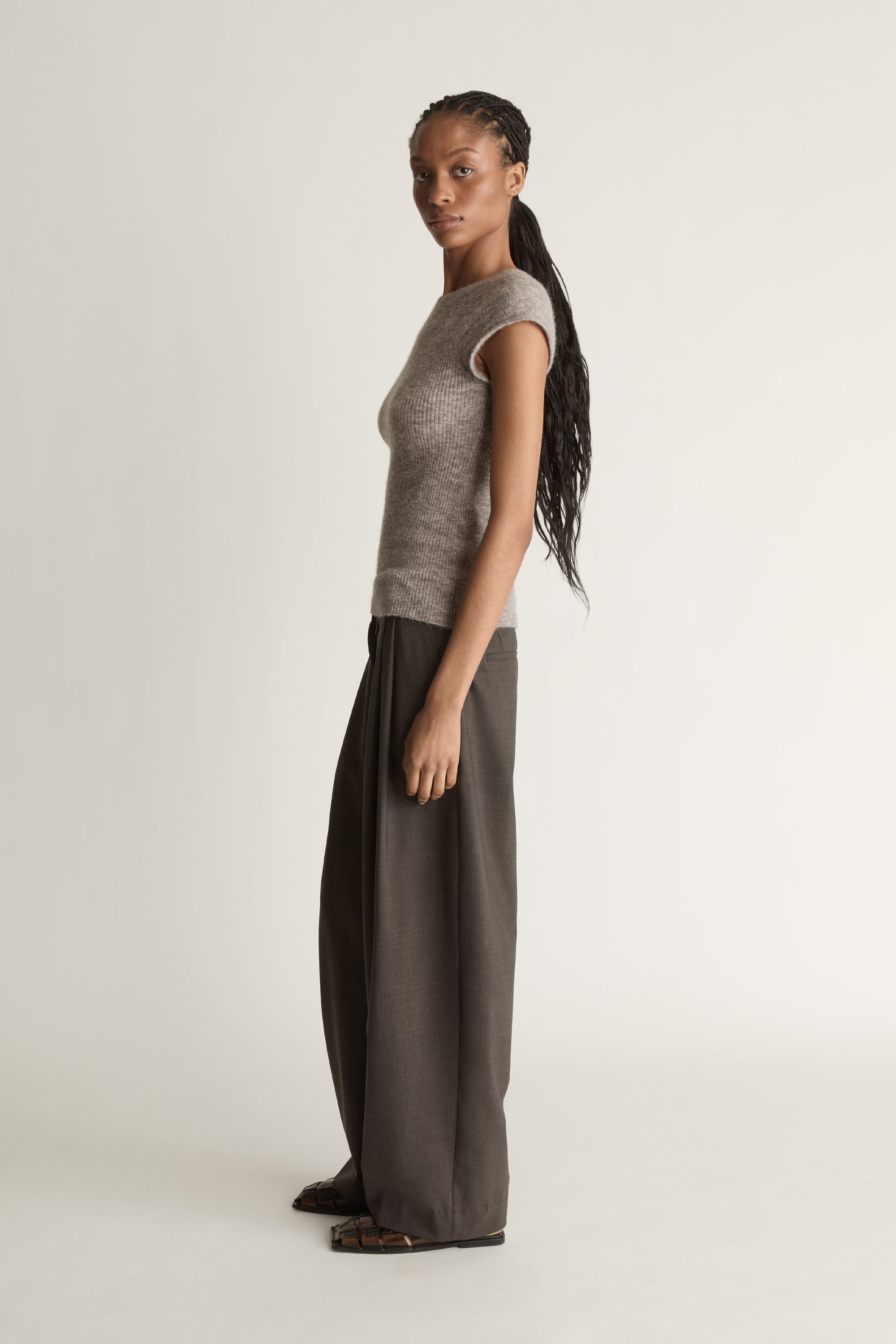 Woman wearing a gray knit top and wide-leg pants on a white background