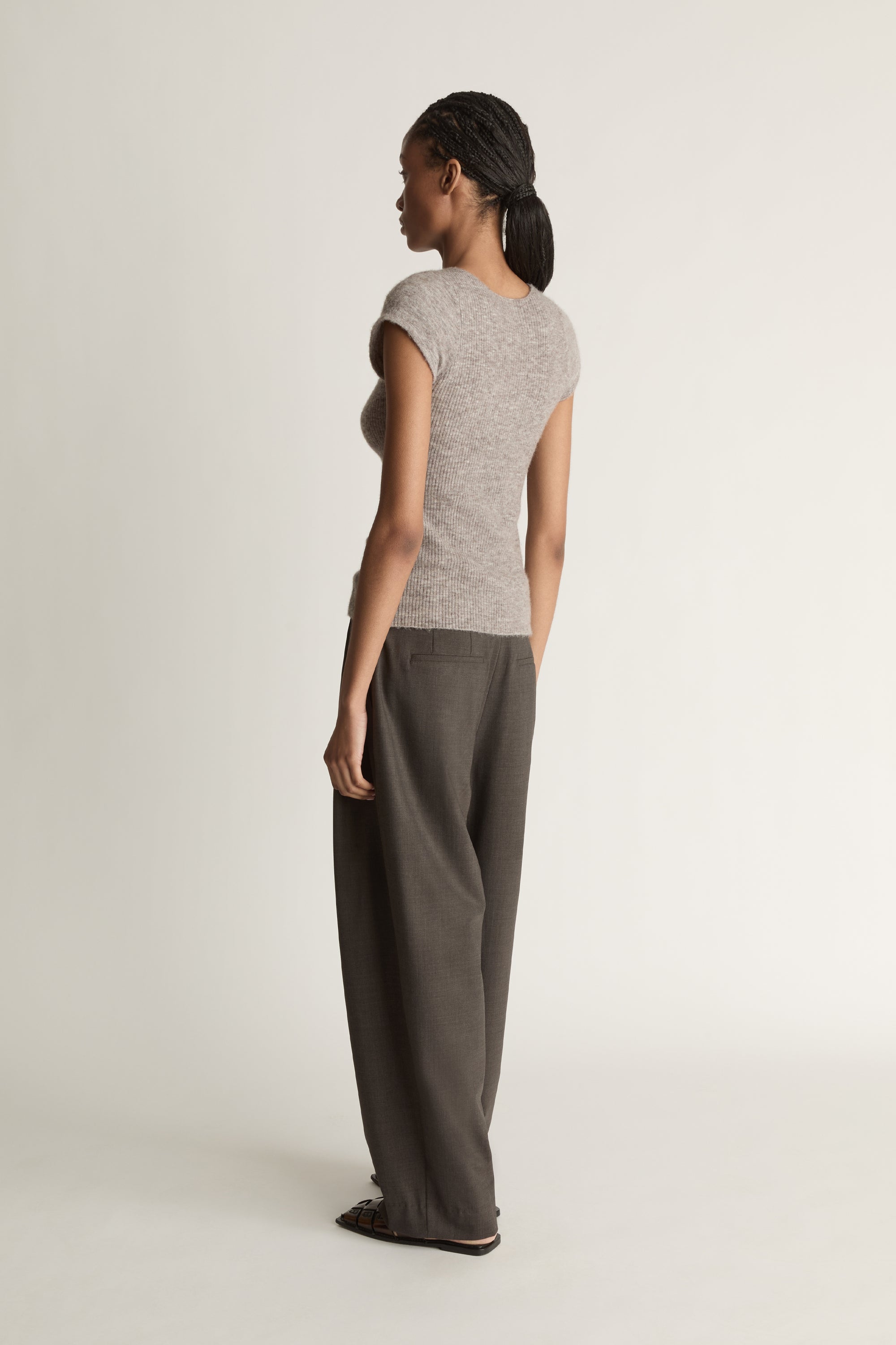 Woman wearing a gray knit top and wide-leg pants on a white background