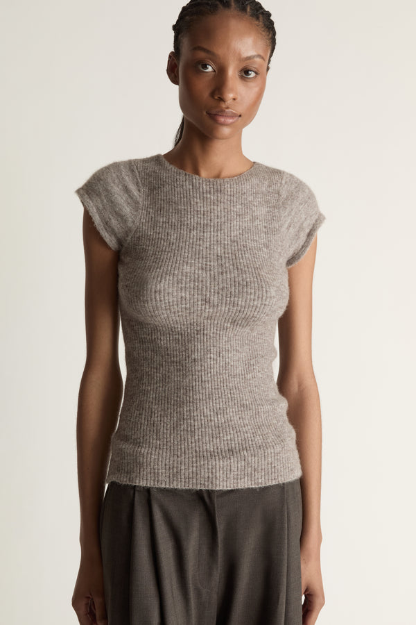 Woman wearing a gray knit top and wide-leg pants on a white background